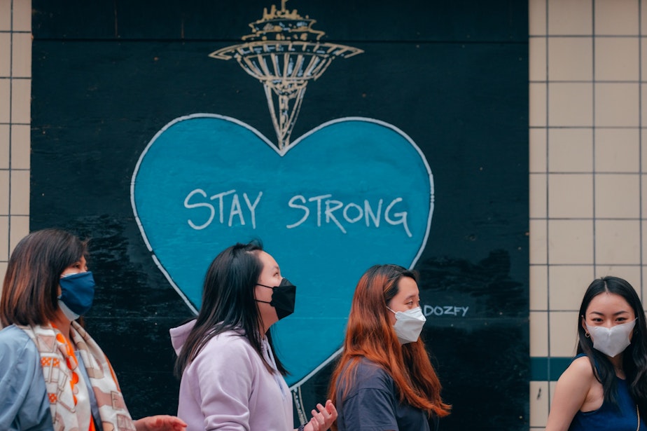 caption: A masked group walks past a mural reading "Stay Strong" on Pike Street in Seattle's Capitol Hill neighborhood on August 3, 2021.