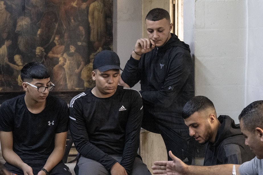 caption: A group of young men, sit and listen to political questions and share their hopes for the future in Ramallah, the West Bank, on Oct. 31, 2023.
