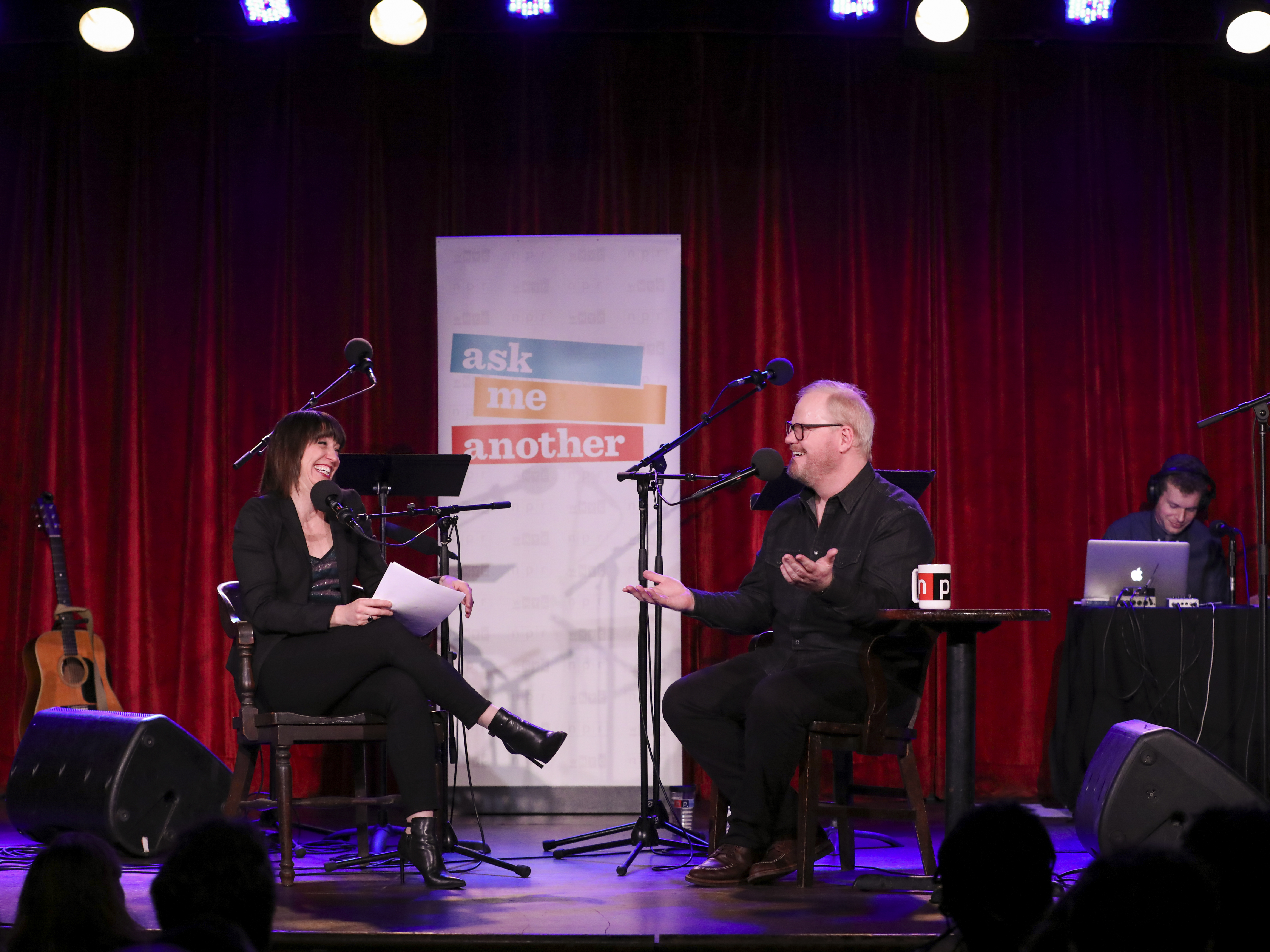 caption: Host Ophira Eisenberg chats with comedian Jim Gaffigan on Ask Me Another at the Bell House in Brooklyn, New York.