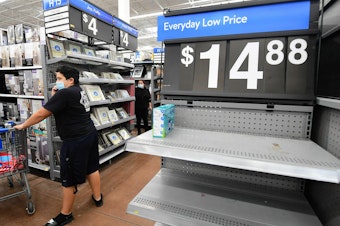 caption: People shop at a Walmart in California in late 2021, with a few empty shelves amid the global supply-chain crisis.
