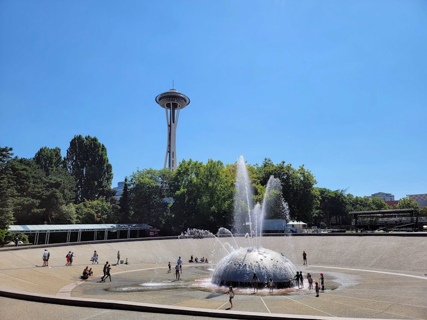 caption: Families run through International Fountain at Seattle Center during a heat wave on Monday, August 14, 2023. 