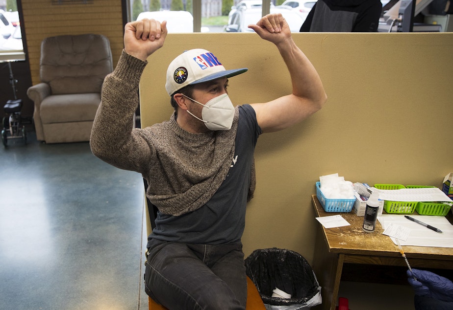 caption: Mike Gaunt of Seattle celebrates after receiving a Covid-19 vaccine from volunteer registered nurse Amy Rioux on Wednesday, April 7, 2021, at Island Drug in Oak Harbor. "I don't want to go crazy and think I have a new lease on life, but it kind of feels like it," said Gaunt. "It's like Christmas." 