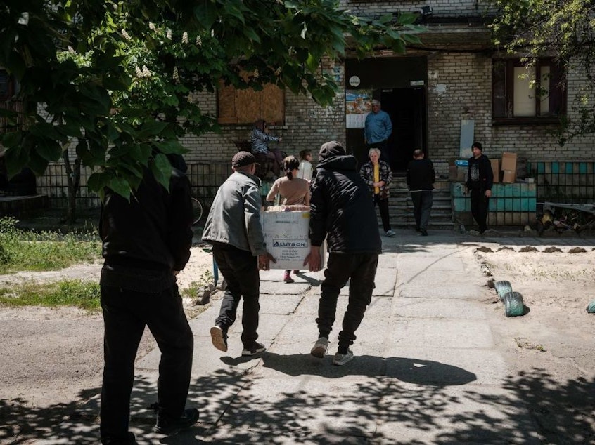 caption: Residents receive food supplies May 7 as volunteers deliver daily from a warehouse of a humanitarian aid distribution center in Severodonetsk, eastern Ukraine