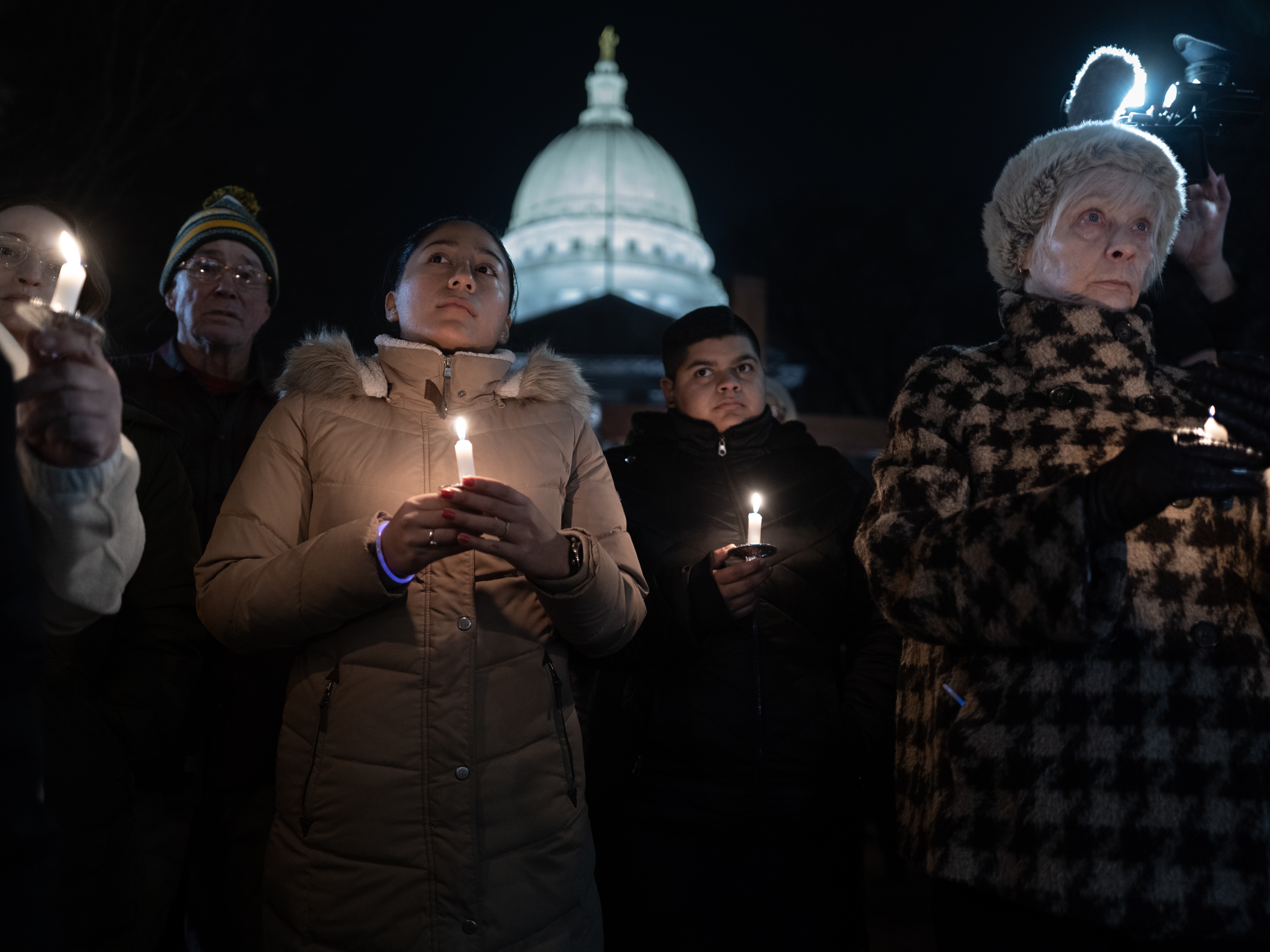 caption: People attend a vigil on the grounds of the Wisconsin State Capitol building to mourn the victims of the shooting at Abundant Life Christian School in Madison, Wis.