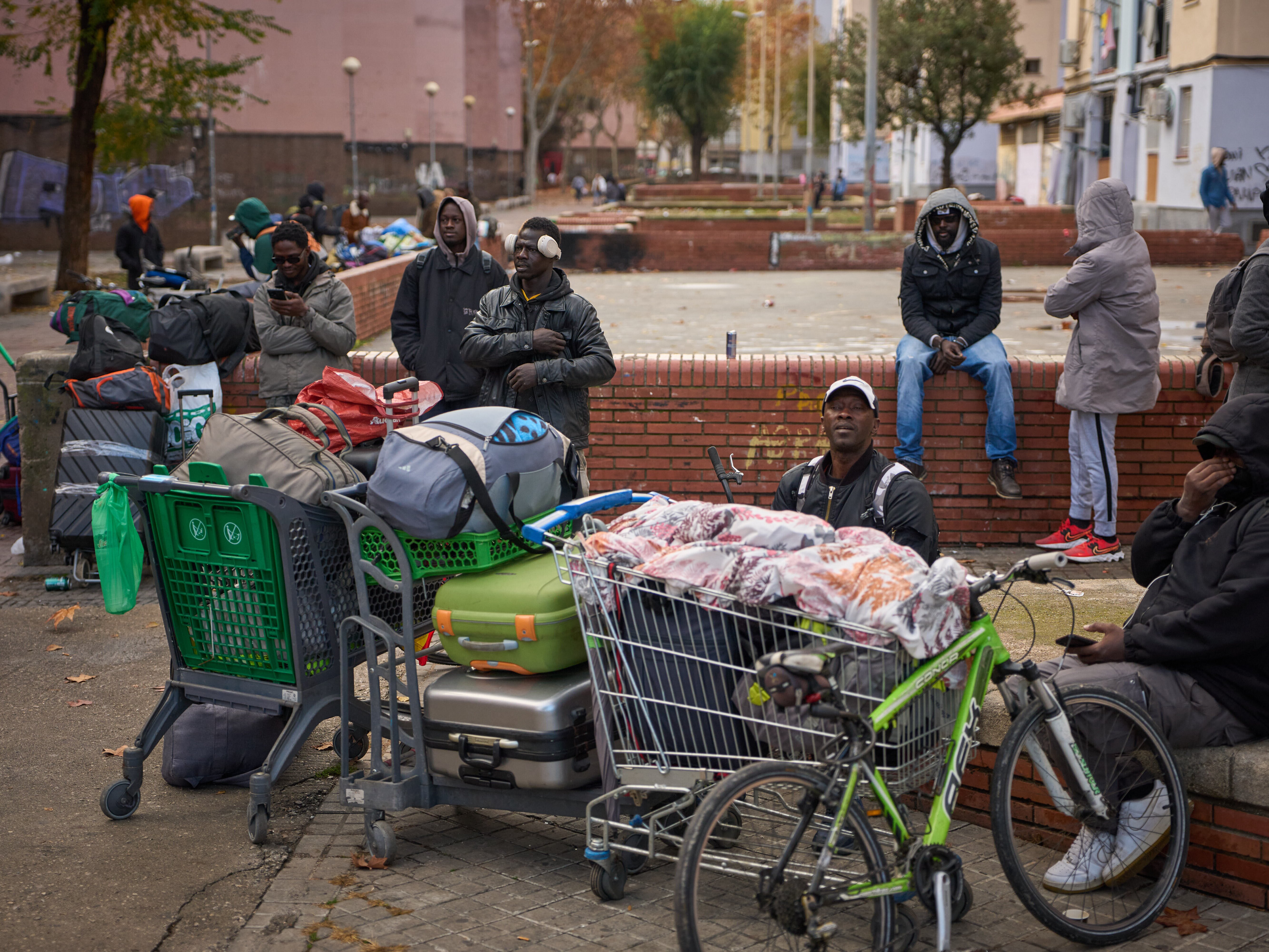 caption: FILE - Migrants sit together with their belongings after being evicted by police from an abandoned school where they had been living in Badalona, near Barcelona, Spain, Wednesday, Dec. 17, 2025.