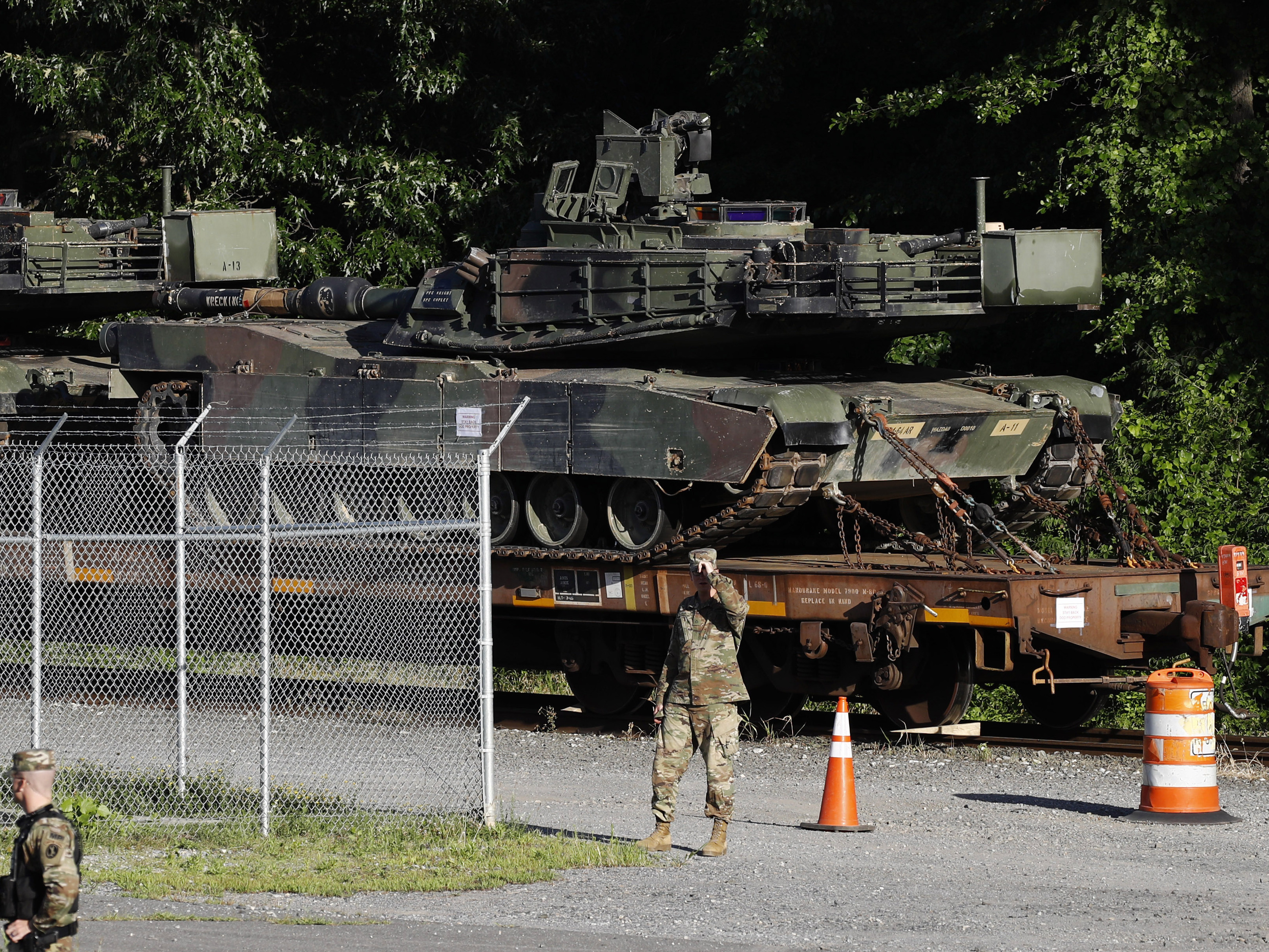 caption: Military police walk near Abrams tanks on a flatcar in a Washington, D.C., rail yard on Monday, ahead of the July 4 celebration that President Trump says will include military hardware.