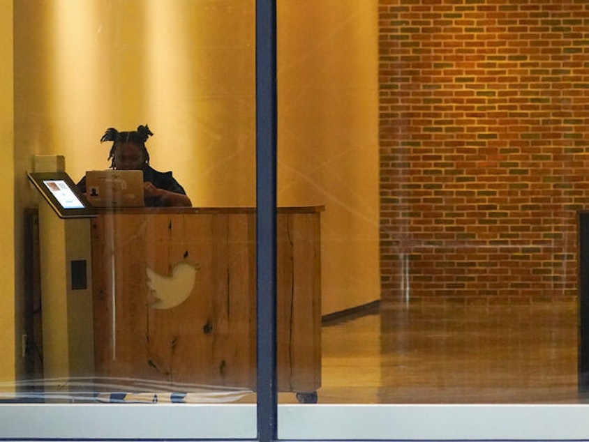 caption: A receptionist works Oct. 26 in the lobby of the building that houses the Twitter office in New York.