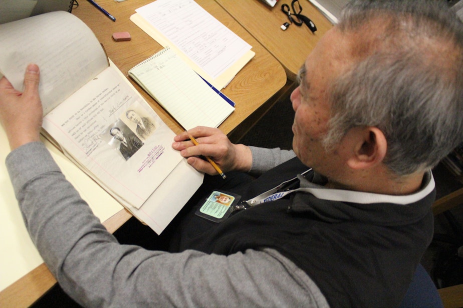 caption: Volunteer Hao Jang Chang looks through a file from the era of the Chinese Exclusion Act at the National Archives in Seattle.