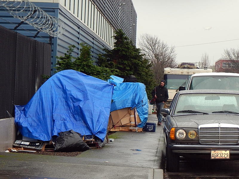 caption: Homeless encampment along a road in the Sodo area of Seattle.
