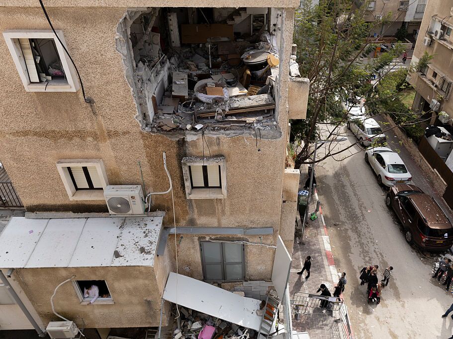 caption: People look at a destroyed apartment after a hit of a ballistic missile fired from Iran, left two injured on Wednesday in Bnei Brak, Israel.