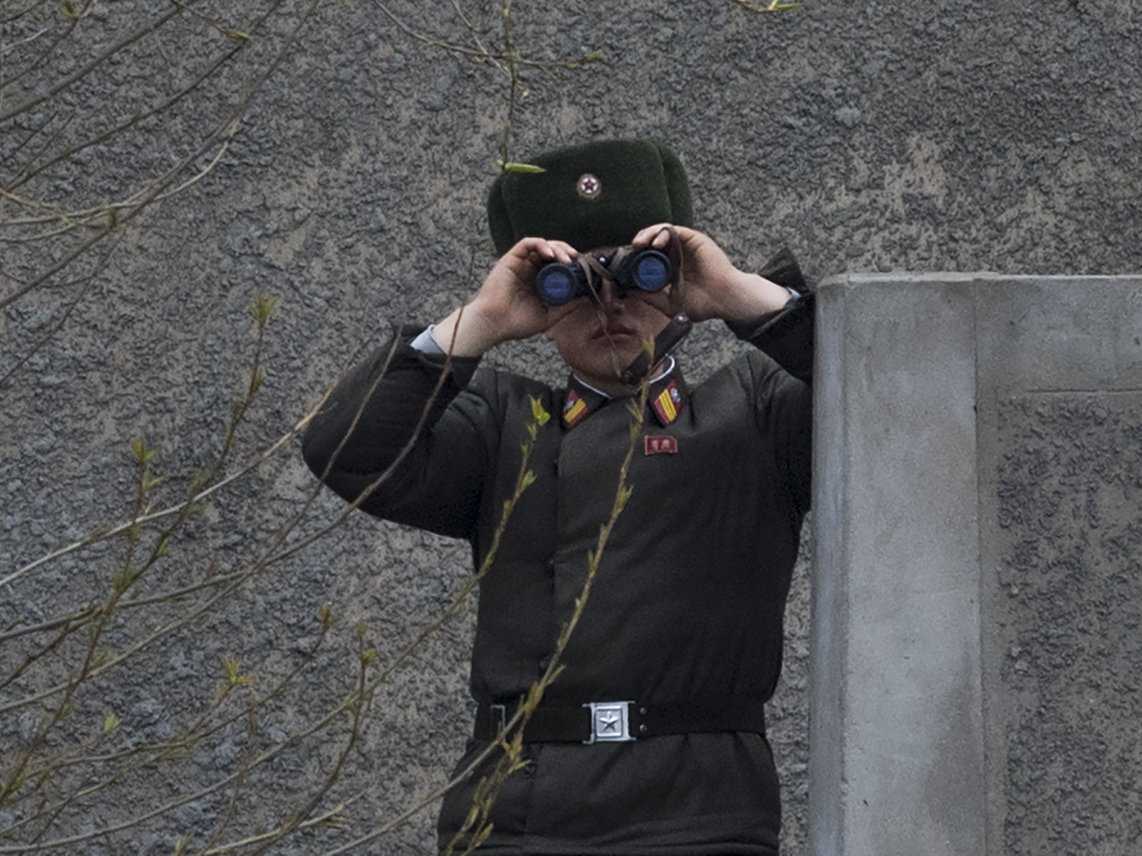 caption: A North Korean soldier looks across the Yalu river near Sinuiju, opposite the Chinese border city of Dandong in April 2017.