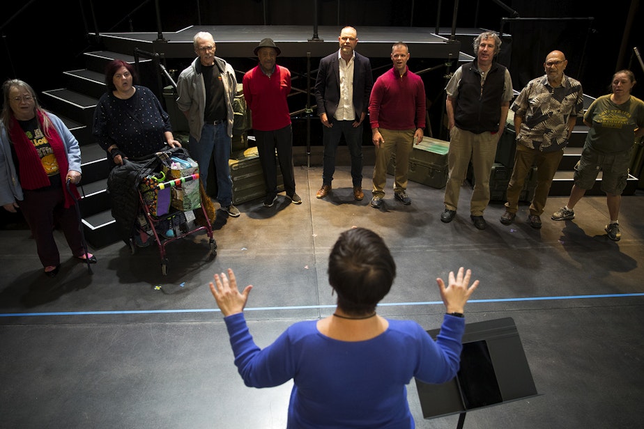 caption: Seattle Opera teaching artist Liz Frazer conducts the veterans choir during a final presentation rehearsal on Thursday, October 31, 2019, at Seattle Opera on Mercer Street in Seattle. 