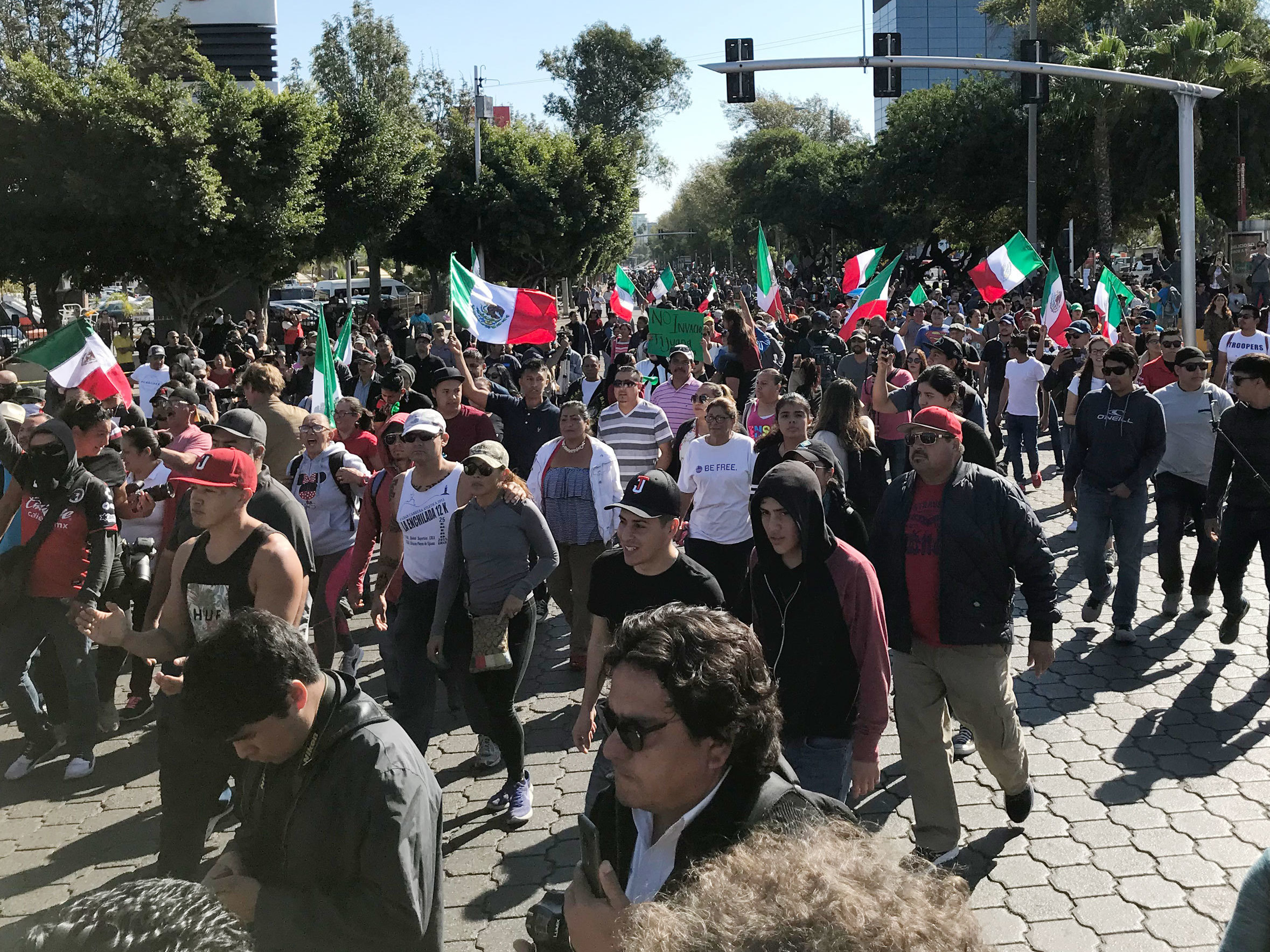 caption: A few hundred people gathered in Tijuana's high-end Rio area on Sunday, to protest against groups migrating from Central American countries.
