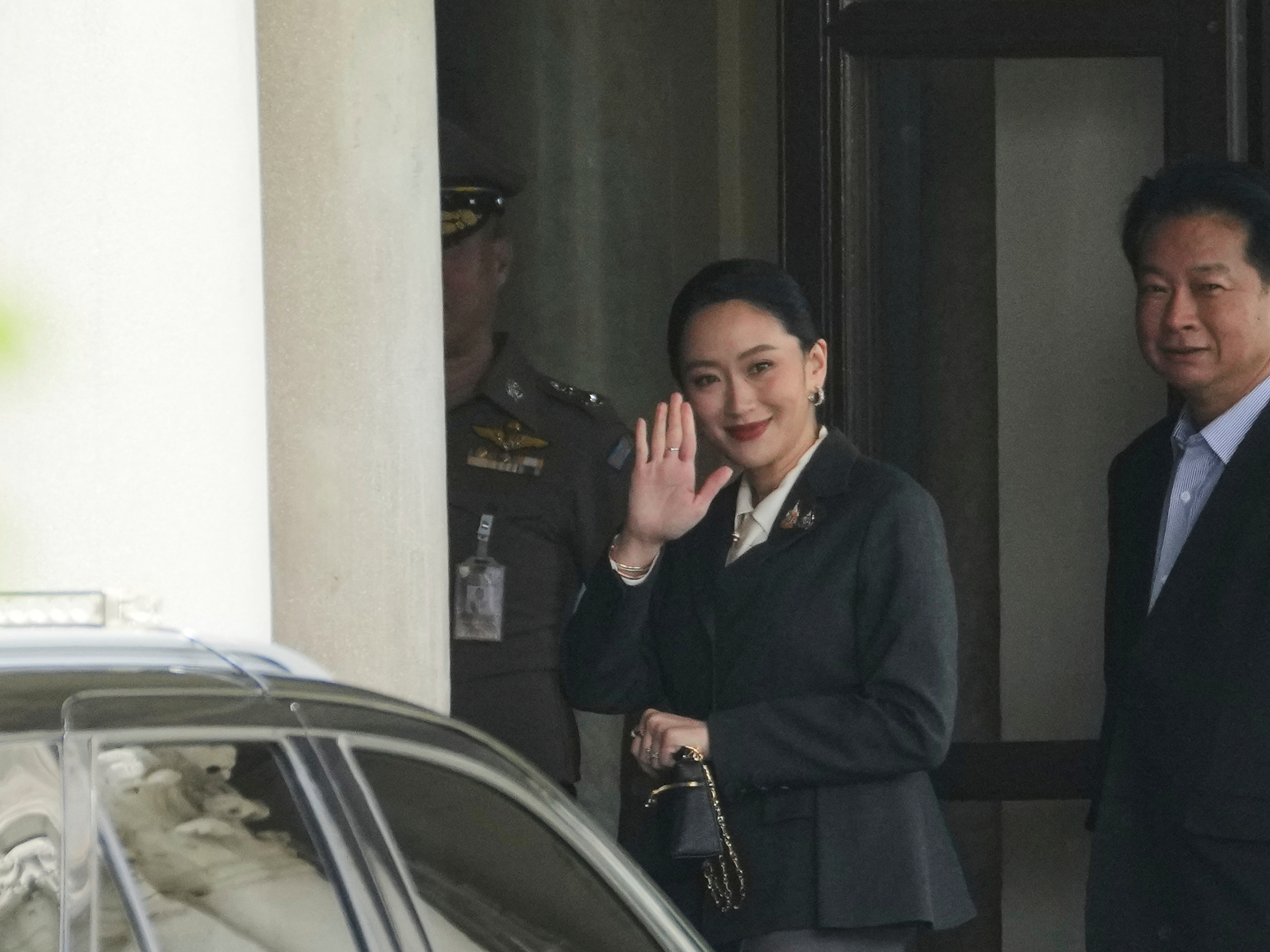 caption: Thailand's suspended Prime Minister Paetongtarn Shinawatra, center, arrives at Government House in Bangkok, Thailand, Friday, Aug. 29, 2025.