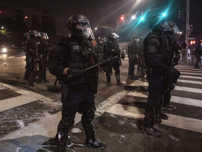 caption: Police stand guard as protesters take to the streets on Sept. 4 in Portland, Ore.