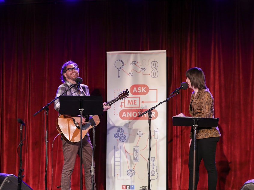 caption: <em>Ask Me Another</em>'s house musician Jonathan Coulton leads a music parody game alongside Ophira Eisenberg at the Bell House in Brooklyn, New York.