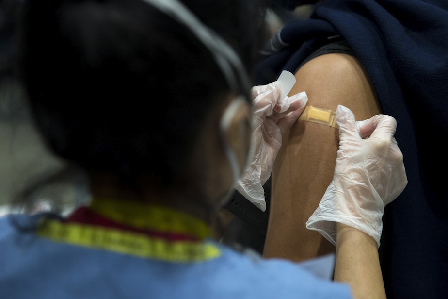 caption: Registered nurse Cecilia Venzon applies a bandaid to Brooke Spearmon's shoulder after administering a Covid-19 vaccine on Saturday, March 13, 2021, at the new civilian-led mass vaccination site at Lumen Field Event Center in Seattle.