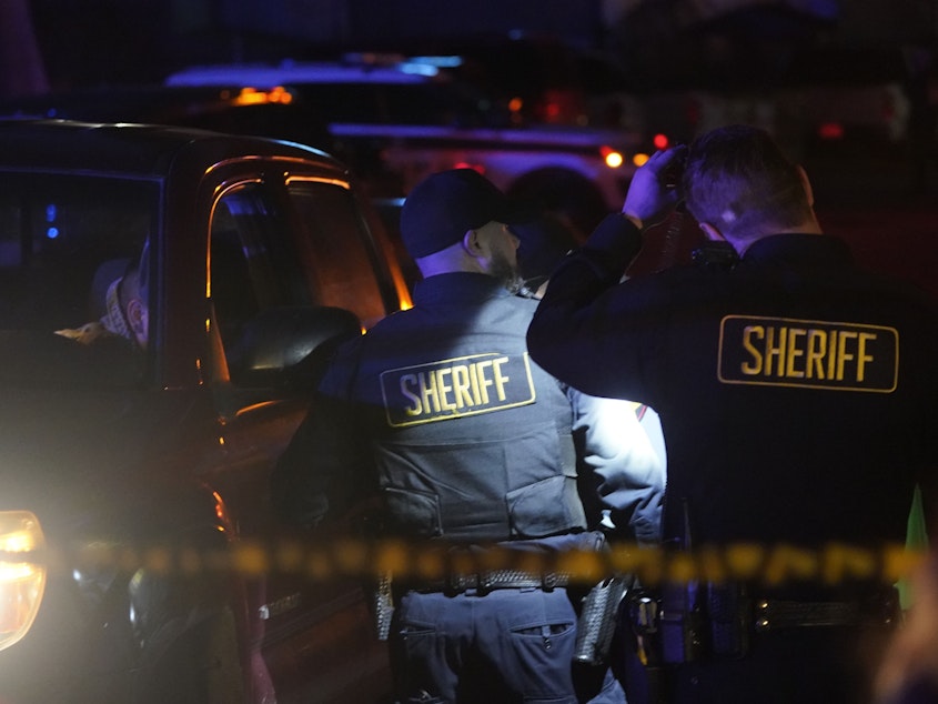 caption: Law enforcement personnel stand at the scene of a shooting on Monday in Half Moon Bay, Calif. Seven people were killed in two related shootings.