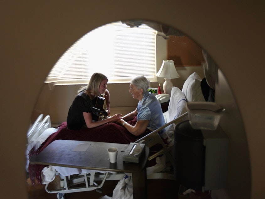 caption: Terminally ill hospice resident Evelyn Breuning, 91, right, sits with music therapist Jen Dunlap in her bed in August 2009 in Lakewood, Colo. The nonprofit hospice, the second oldest in the United States, accepts the terminally ill regardless of their ability to pay, although most residents are covered by Medicare.