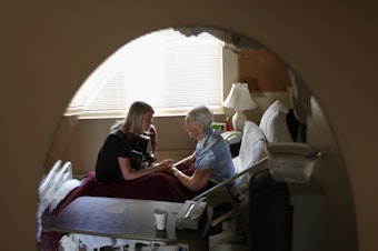 caption: Terminally ill hospice resident Evelyn Breuning, 91, right, sits with music therapist Jen Dunlap in her bed in August 2009 in Lakewood, Colo. The nonprofit hospice, the second oldest in the United States, accepts the terminally ill regardless of their ability to pay, although most residents are covered by Medicare.