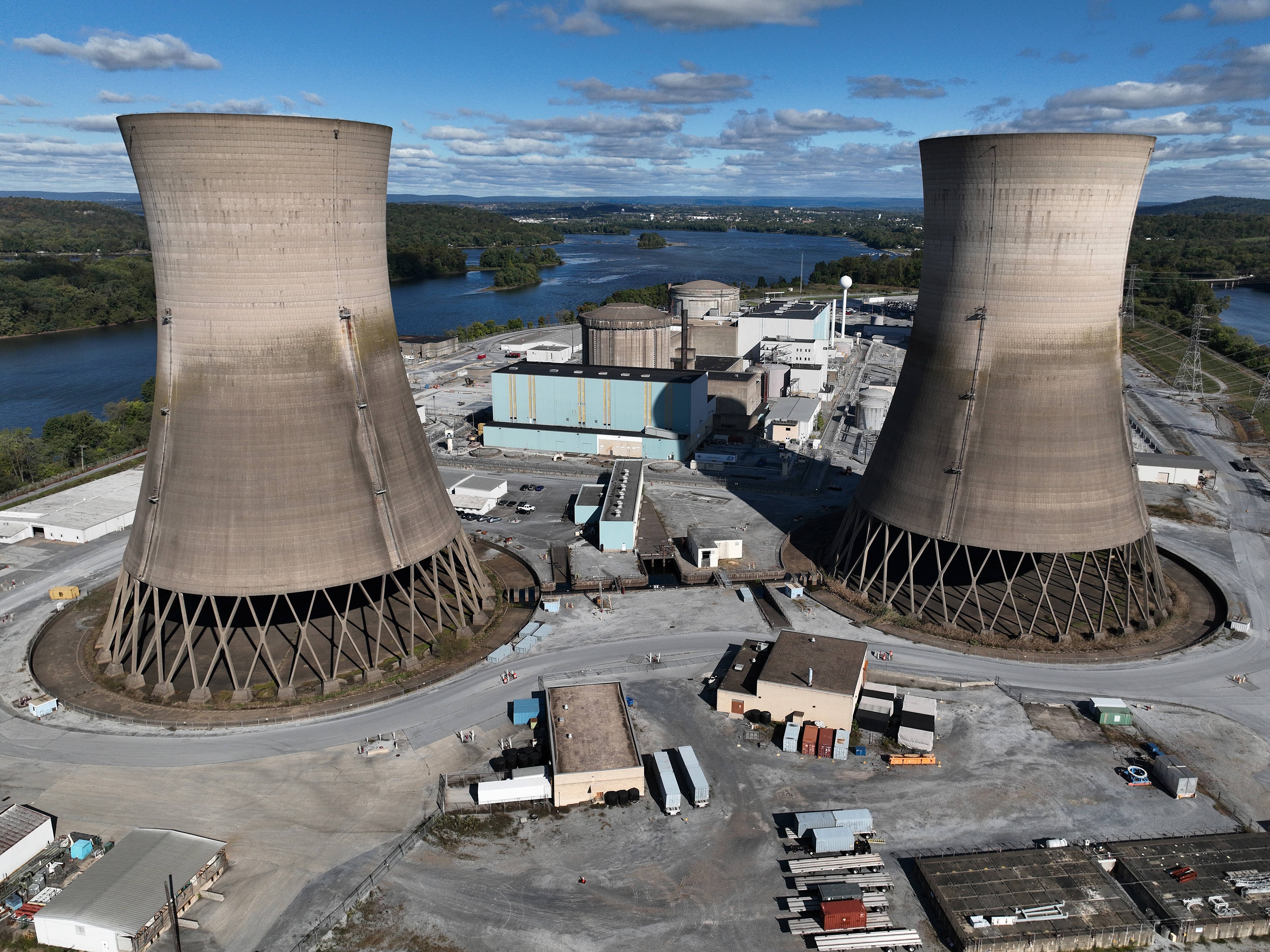 caption: The shuttered Three Mile Island nuclear power plant stands in the middle of the Susquehanna River on October 10, 2024. One of the plant's two reactors partly melted down in 1979, but the second one operated for decades before it was closed. It is now set to be restarted as early as 2028, pending approval by the Nuclear Regulatory Commission.