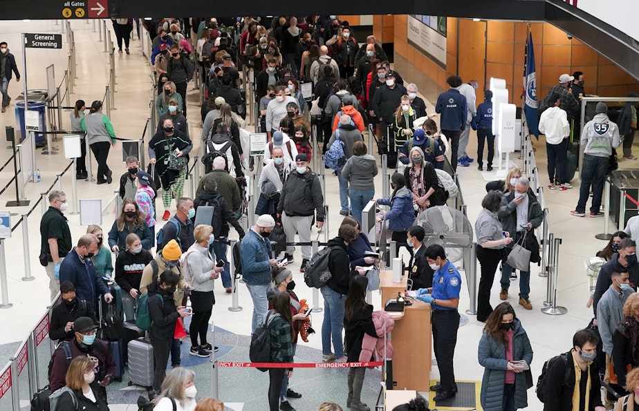 caption: Travelers wear masks as they wait in a line for a TSA security check, Dec. 10, 2021, at Seattle-Tacoma International Airport in Seattle. 