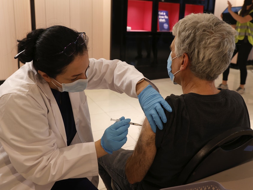 caption: Safeway pharmacist Shahrzad Khoobyari administers a Pfizer-BioNTech COVID-19 booster shot into the arm of Norman Solomon in San Rafael, Calif., in October.