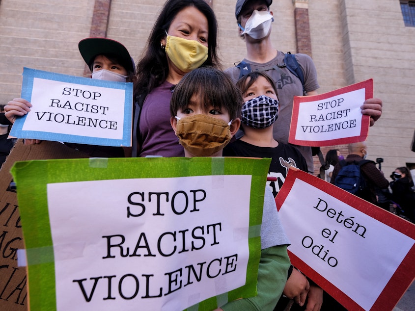 caption: A family wearing face masks and holding signs take part in a rally "Love Our Communities: Build Collective Power" to raise awareness of anti-Asian violence, at the Japanese American National Museum in Little Tokyo in Los Angeles, California, on March 13.