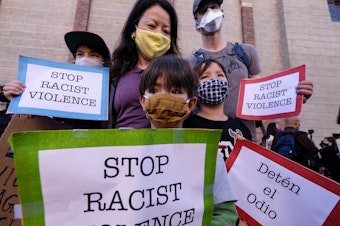 caption: A family wearing face masks and holding signs take part in a rally "Love Our Communities: Build Collective Power" to raise awareness of anti-Asian violence, at the Japanese American National Museum in Little Tokyo in Los Angeles, California, on March 13.