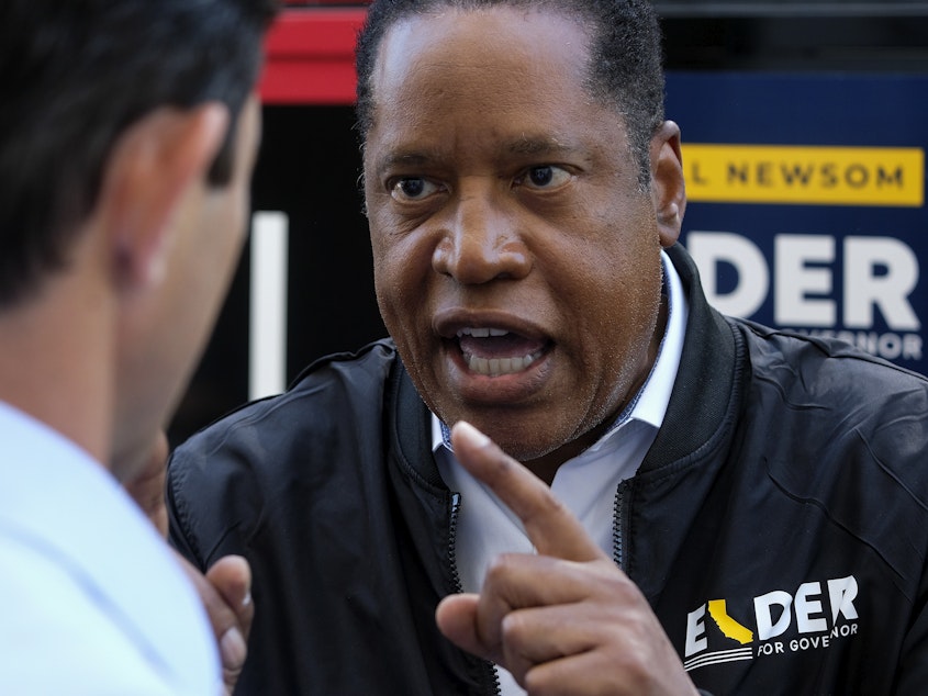 caption: Republican conservative radio show host Larry Elder argues with a TV reporter during an interview after visiting Philippe The Original Deli during a campaign for the California gubernatorial recall election on Monday, Sept. 13, 2021, in Los Angeles.