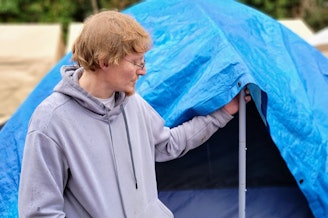 caption: Carlos "Los" Paz begins to take down his tent at Sunnydale Village in Burien on Monday, Feb. 5, 2024.