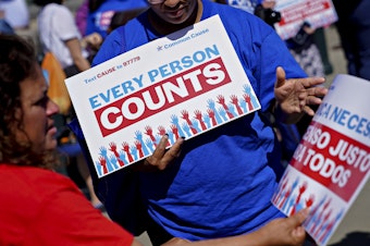 caption: A demonstrator hands out a sign about the 2020 census outside the U.S. Supreme Court in Washington, D.C., in 2019. The Census Bureau is projecting the first set of census numbers won't be ready until February, Trump administration attorneys told a federal judge on Monday.