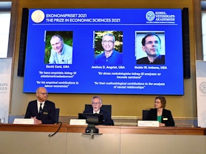 caption: Goran K. Hansson (C), Permanent Secretary of the Royal Swedish Academy of Sciences, and Nobel Economics Prize committee members Peter Fredriksson (L) and Eva Mork (R) give a press conference to announce the winners of the 2021 Sveriges Riksbank Prize in Economic Sciences in Memory of Alfred Nobel.