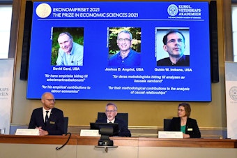 caption: Goran K. Hansson (C), Permanent Secretary of the Royal Swedish Academy of Sciences, and Nobel Economics Prize committee members Peter Fredriksson (L) and Eva Mork (R) give a press conference to announce the winners of the 2021 Sveriges Riksbank Prize in Economic Sciences in Memory of Alfred Nobel.