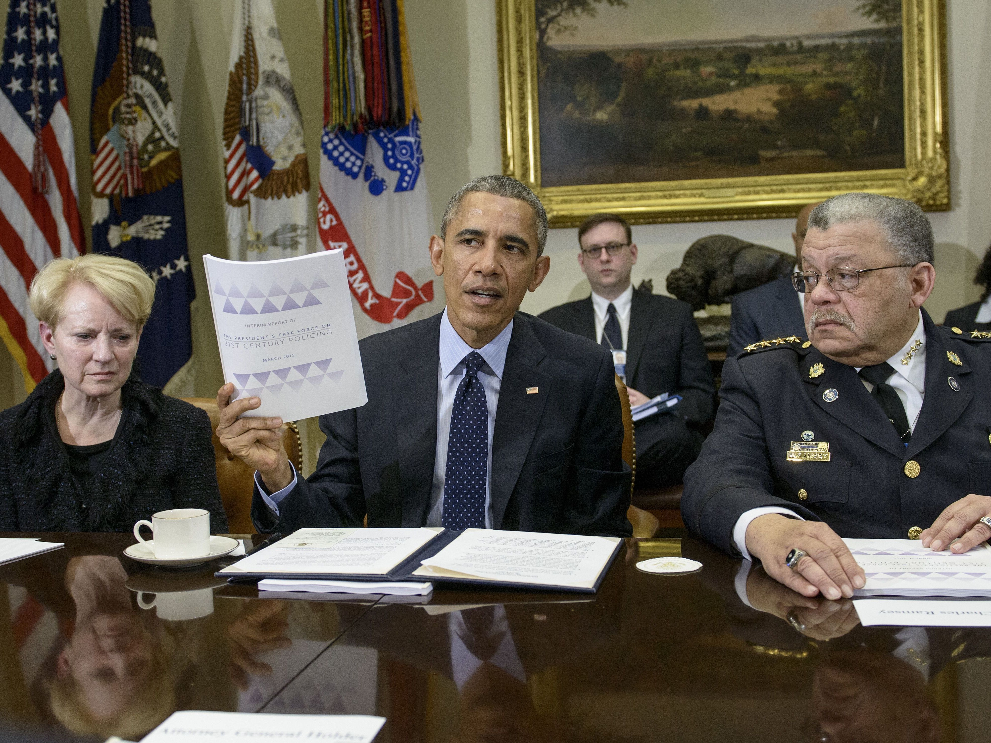 caption: Laurie Robinson, left, professor of criminology at George Mason University, and Charles Ramsey, right, Philadelphia police commissioner, listen while President Obama discusses law enforcement recommendations from his Task Force on 21st Century Policing in March 2015.