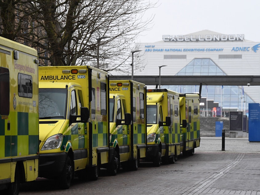 caption: Ambulances are parked outside the NHS Nightingale hospital at the ExCeL center in east London on Friday. Hospitals in the U.K. are preparing for an influx of patients as the coronavirus continues to spread.