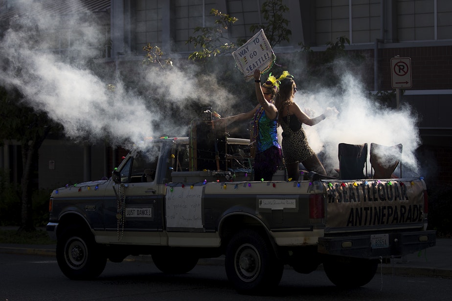 caption: Members of the Seattle Quarantine Parade, Lindsey Hornickel and Darcy Newby, right, dance while driving through the Wallingford neighborhood on Friday, May 8, 2020, in Seattle. 