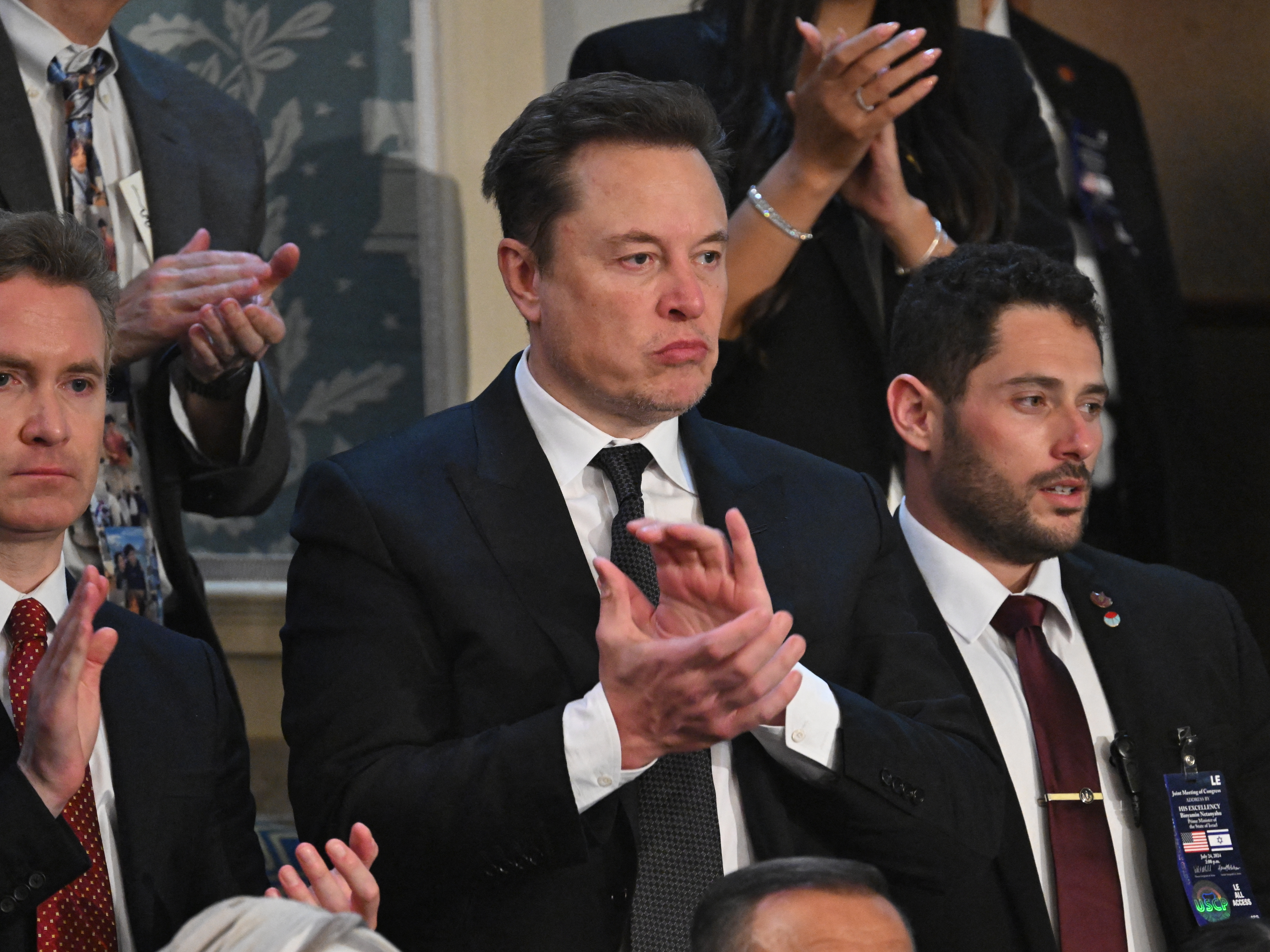 caption: Tesla CEO Elon Musk applauds as Israeli Prime Minister Benjamin Netanyahu speaks to a joint meeting of Congress at the U.S. Capitol on Wednesday. Musk has endorsed former President Donald Trump's campaign — but he says he isn't donating $45 million each month to the cause.