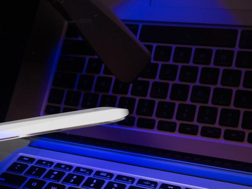 caption: A hand-held ultraviolet C wand is waved over the surface of a computer keyboard.