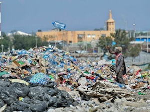 caption: A man picks through plastic waste at a garbage dump in Kenya.