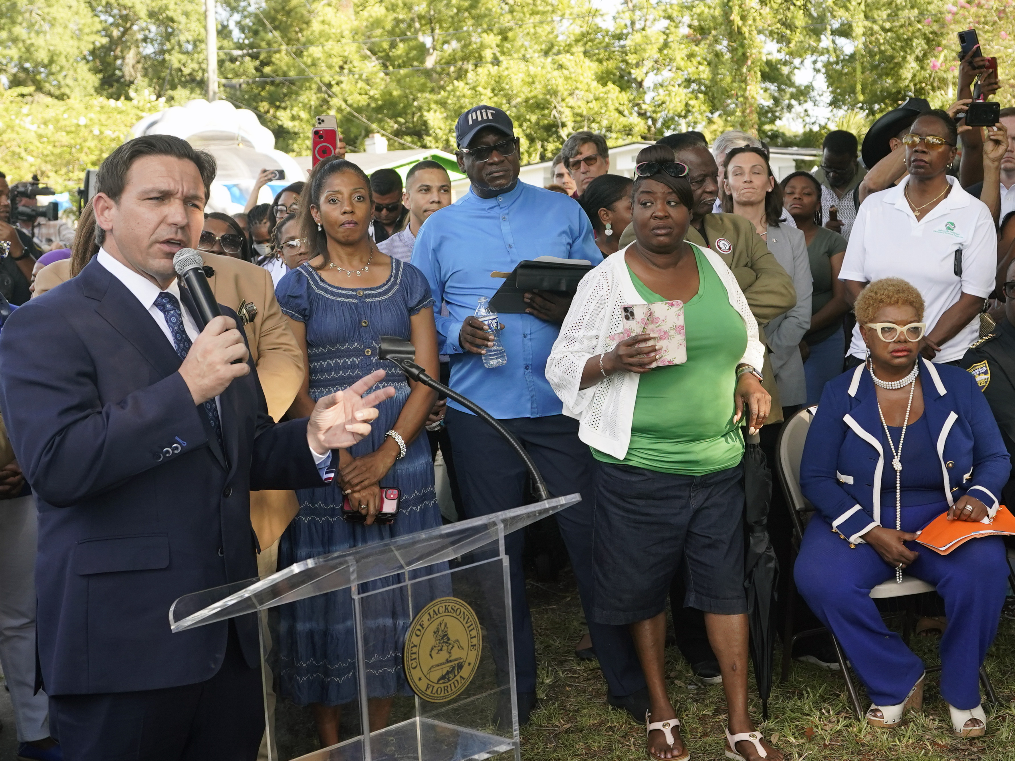 caption: Florida Gov. Ron DeSantis, left, speaks at a prayer vigil on Sunday for the victims of a mass shooting that took place Saturday in Jacksonville, Fla.