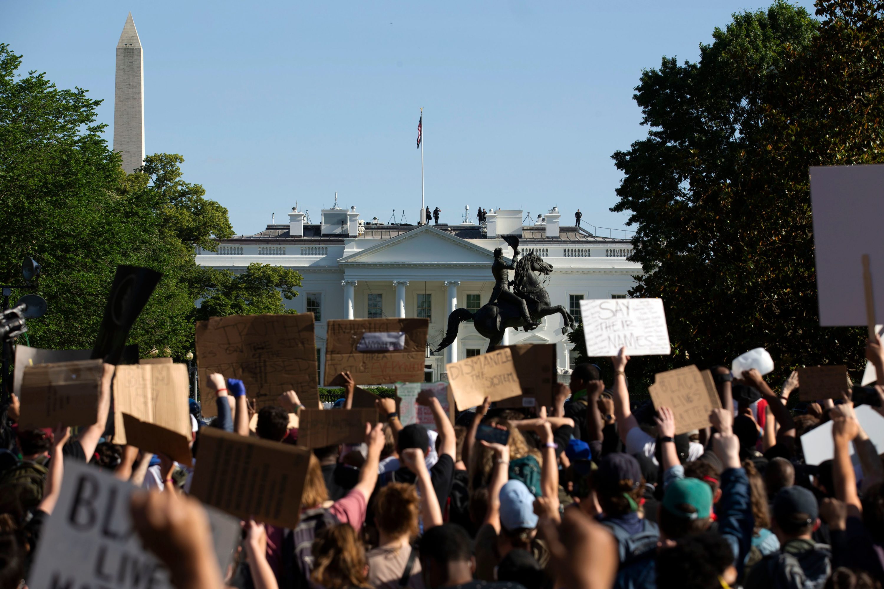 caption: Demonstrators hold up placards protest outside of the White House, over the death of George Floyd in Washington D.C. on June 1, 2020. (JOSE LUIS MAGANA/AFP via Getty Images)