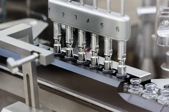 caption: Rubber stoppers are placed onto filled vials of the investigational drug remdesivir at a Gilead manufacturing site in the United States.