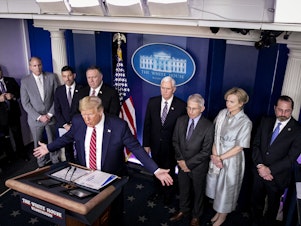 caption: President Trump, center left, speaks during a Coronavirus Task Force news conference in the briefing room of the White House on Friday, March 20, 2020.