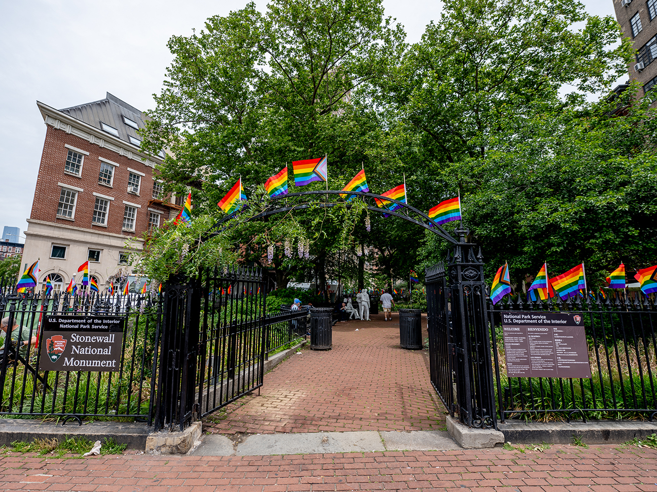 caption: Pride flags decorate the Stonewall National Monument at Christopher Park in front of the Stonewall Inn. Many Pride events this year are more subdued due to pandemic precautions.