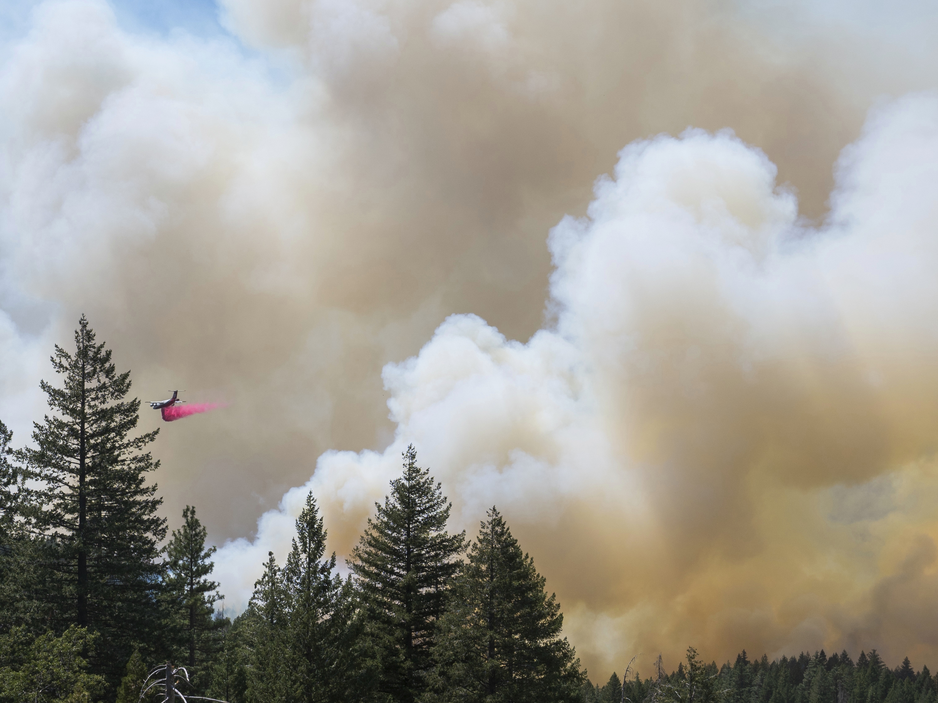 caption: A plane drops fire retardant on the Park Fire near Forest Ranch, Calif., Sunday, July 28, 2024. Smoke from the fire is causing air quality issues across the Northwest and parts of Canada.