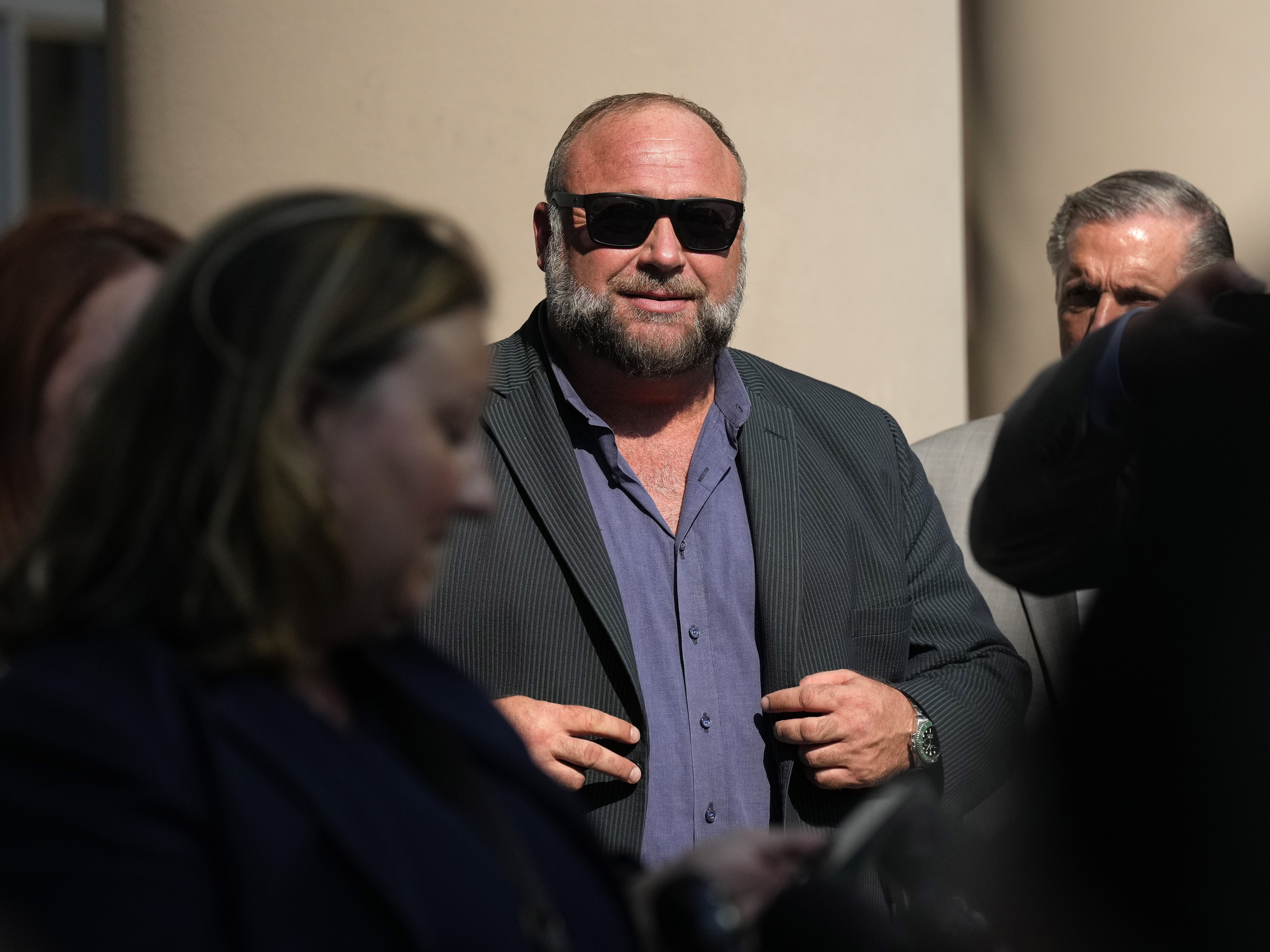 caption: Right-wing conspiracy theorist Alex Jones stands outside the federal courthouse after a June bankruptcy hearing in Houston.