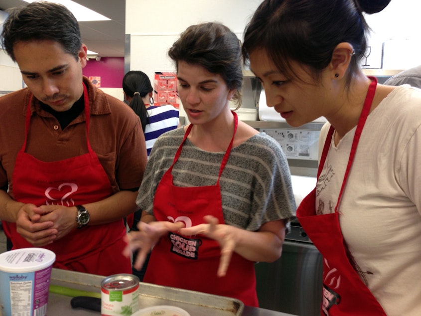 caption: Medical residents Bryn Chowchuvech, Bari Laskow  and Tiffany Ho discuss strategy for making their spaghetti dish.