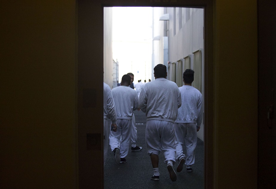 caption: Detainees walk toward the outdoor recreation area on Tuesday, September 10, 2019, at the Northwest Detention Center, recently renamed the Northwest ICE Processing Center, in Tacoma.