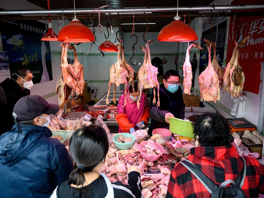 caption: People wearing protective face masks shop at a chicken stall at a wet market in Shanghai on Feb. 13.